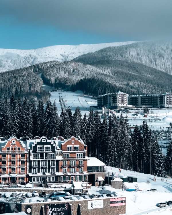 Charming hotel buildings nestled in a snowy mountain landscape with evergreen trees and clear skies.