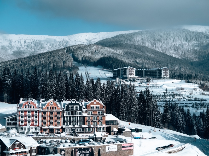 Charming hotel buildings nestled in a snowy mountain landscape with evergreen trees and clear skies.