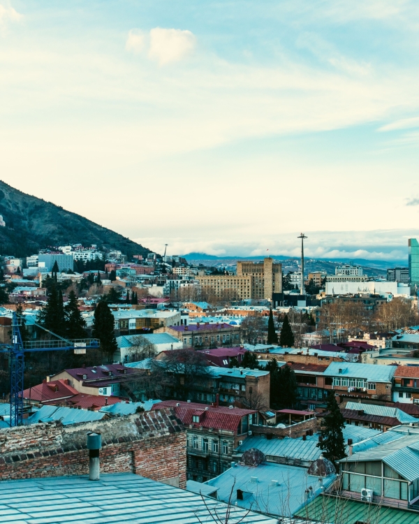 Aerial view of Tbilisi showcasing iconic landmarks and vibrant cityscape under a clear sky.
