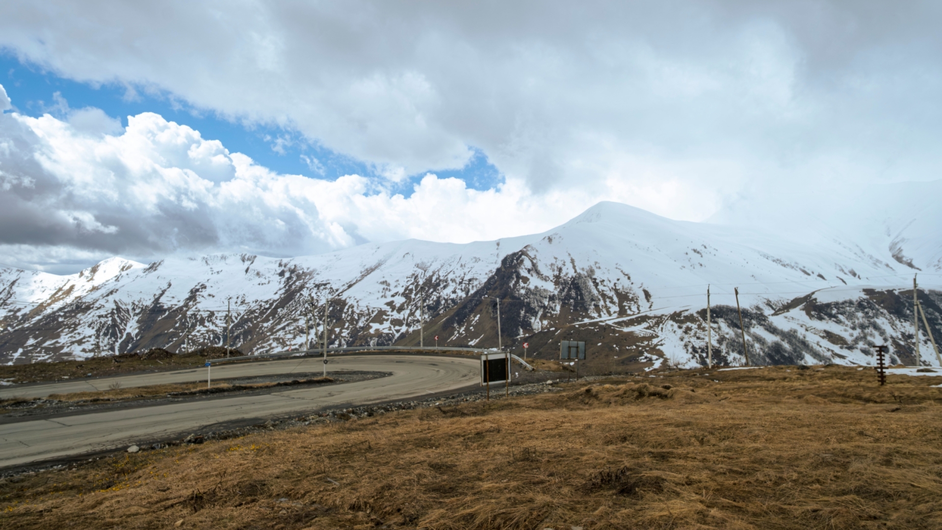 Captivating winter landscape showcasing snowy mountains and a curving road under dramatic skies.