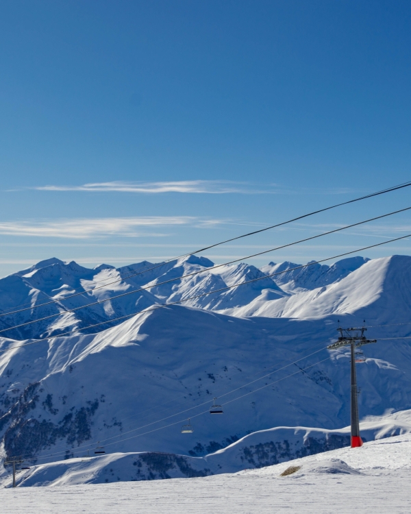 Breathtaking view of skiers and snow-covered peaks in Gudauri, Georgia, a popular winter sports destination.