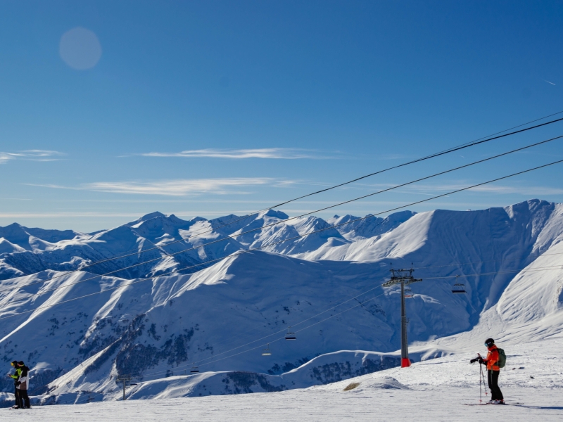 Breathtaking view of skiers and snow-covered peaks in Gudauri, Georgia, a popular winter sports destination.