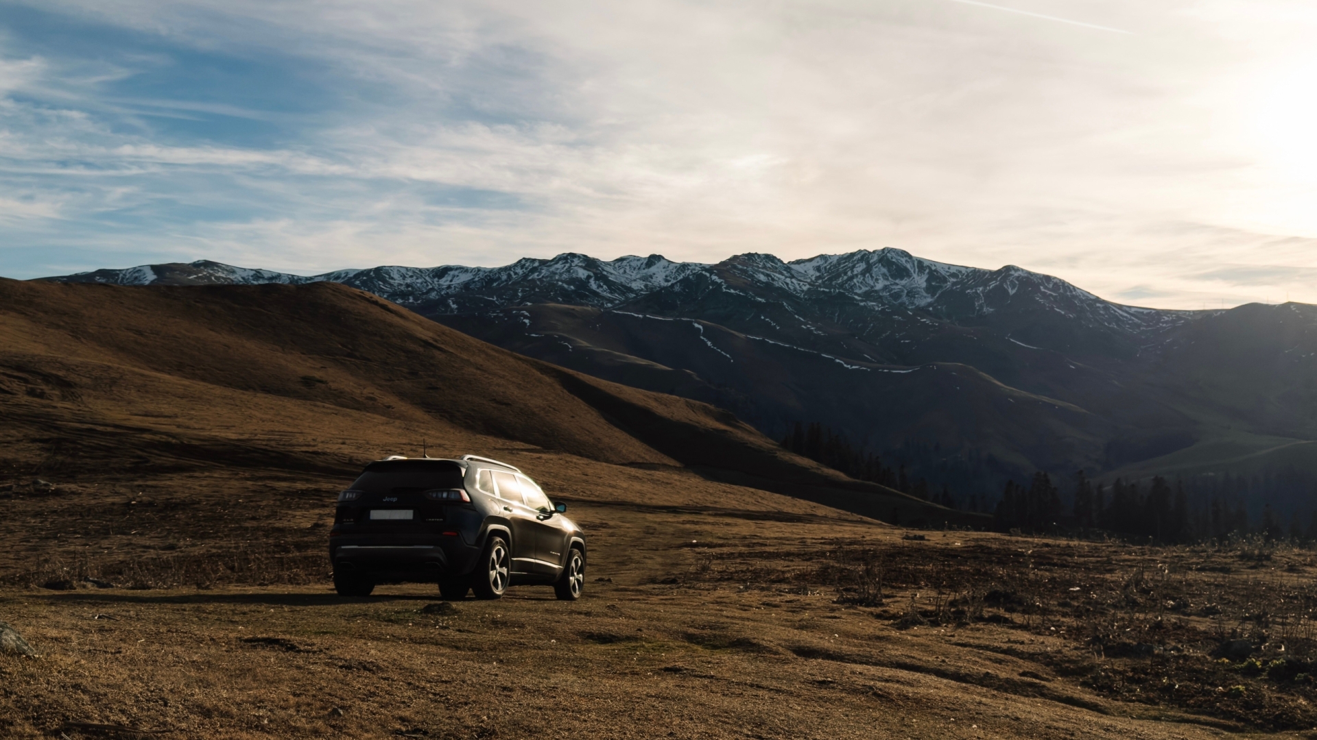 A stunning view of the Georgian mountains in Bakhmaro with an SUV under a beautiful sky.