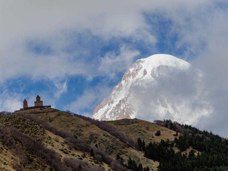 Scenic view of Gergeti Trinity Church with Mount Kazbegi in the background, Georgia's majestic landscape.